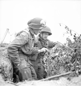 Two soldiers dressed in battle dress with helmets probably looking at a map.